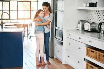 Mom, girl and smile with hug in kitchen for motherhood,...