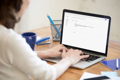 Business lady in office typing reply to corporate email.