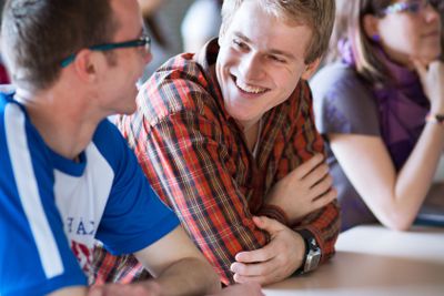 Handsome college student sitting in a classroom full of...