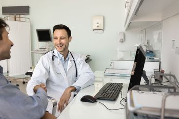 Happy sonographer doctor shaking hands with male patient