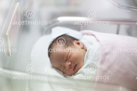 new born infant asleep in the blanket in delivery room
