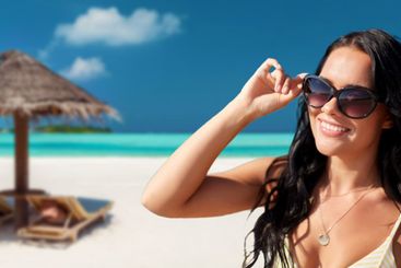 smiling young woman in sunglasses on summer beach