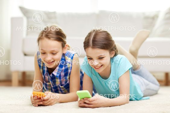 happy girls with smartphones lying on floor