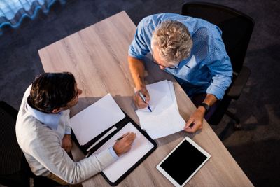 Two businessmen reading a document and interacting