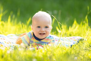 Baby boy with apple on family garden picnic