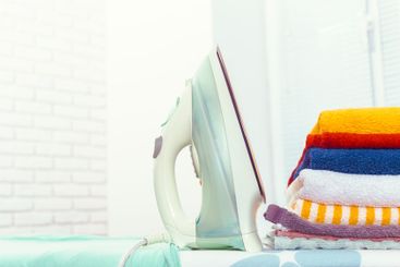 Iron on ironing board on light home interior background