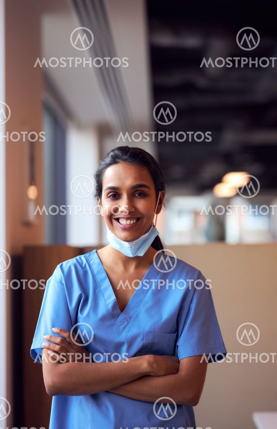 Smiling Female Doctor With Face Mask Wearing Scrubs In...