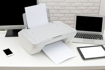Home office workspace with printer, laptop, tablet and...