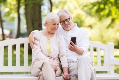 happy senior couple with smartphone at park