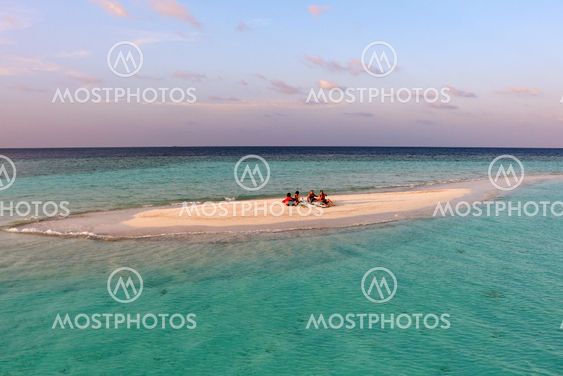 small island with relaxing people in the Maldives sea