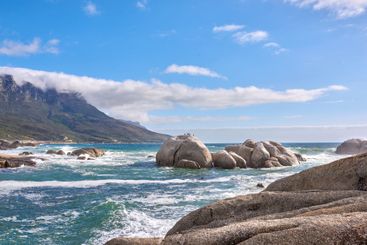 Rocks, sea and mountain on horizon, sky and clouds with...