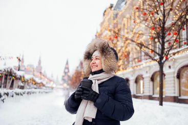 A young woman in winter casual clothes holds a cup of...