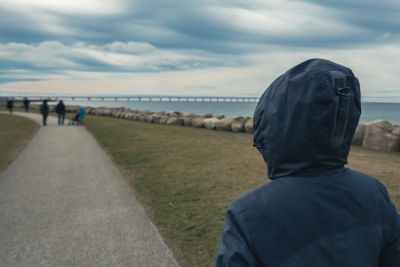 Lonely hooded female person from behind standing at...