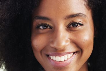 Black woman, portrait and smile in closeup, afro or...