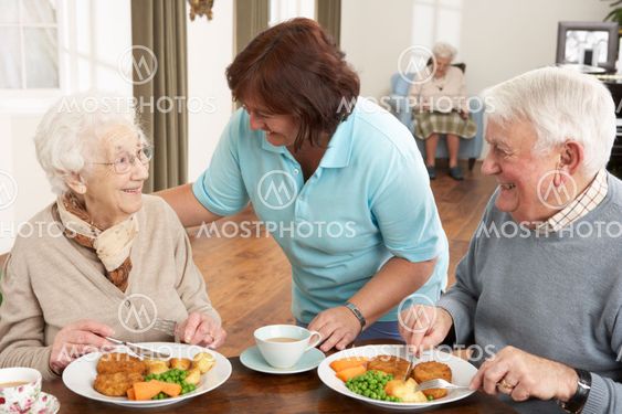 Senior Couple Being Served Meal By Carer
