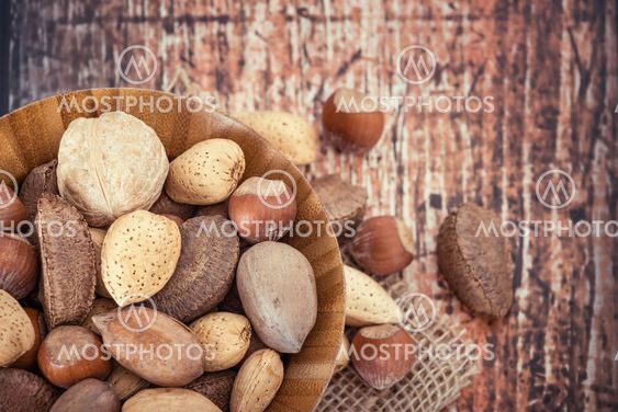 Mix nuts in a wooden bowl against rustic background