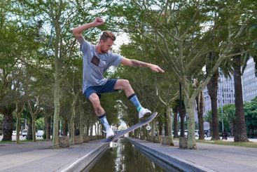 Skateboard, jump and river with man in city for culture,...