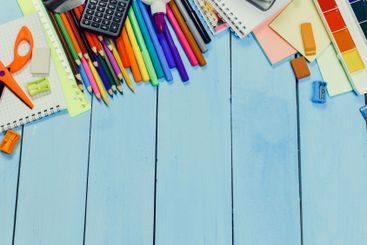 Colorful school supplies spread across a wooden desk...