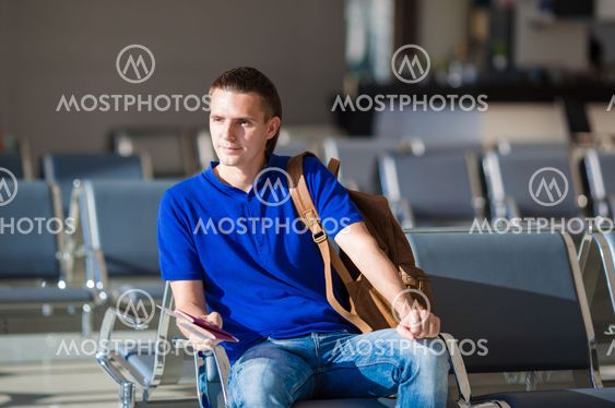 Young man holding passports and boarding pass at airport