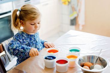 Excited little toddler girl coloring eggs for Easter....