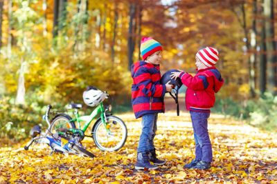 Two little kid boys with bicycles in autumn forest