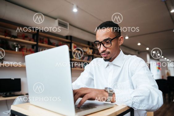 Handsome african businessman typing by laptop computer.