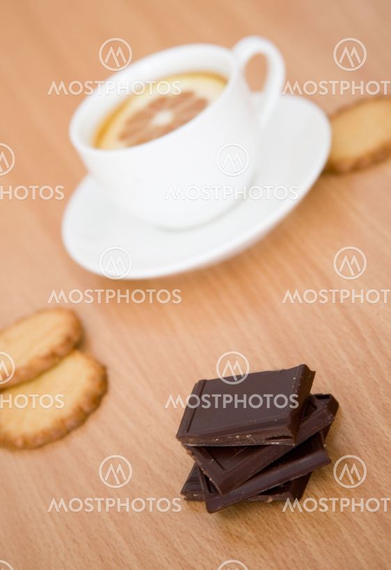 Cup of black tea with lemon, sugar, biscuits and chocolate. Focus on chocolate