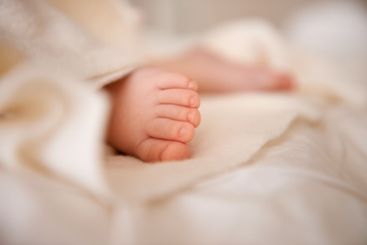 Baby, feet and toes or blanket as closeup for childhood...