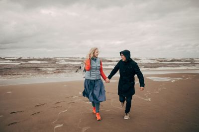 happy young couple holding hands and running on seashore...