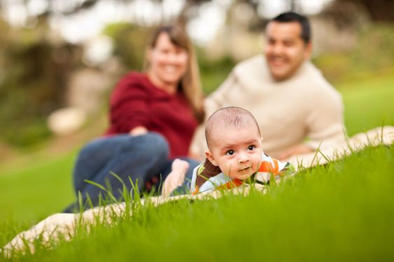 Happy Baby Boy and Mixed Race Parents Playing in the Park