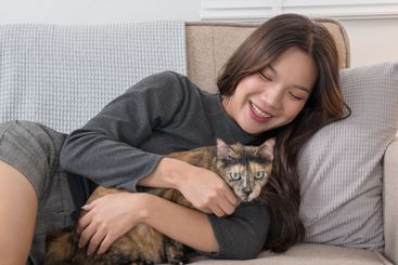 A woman lying on a couch, lovingly cuddling with her...