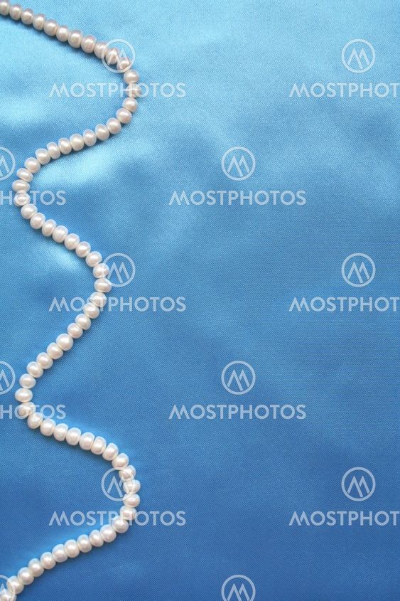Pearls on the smooth elegant blue silk as background