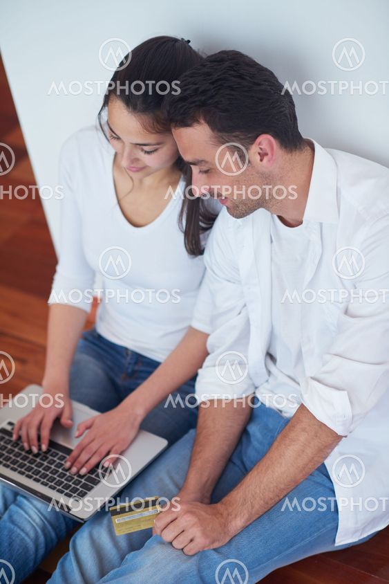 relaxed young couple working on laptop computer at home