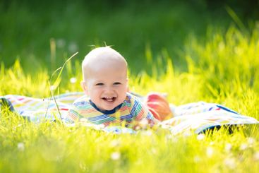 Baby boy with apple on family garden picnic