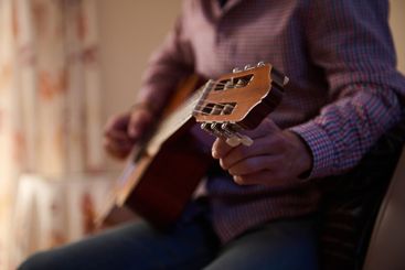 Person playing acoustic guitar indoors during a cozy...