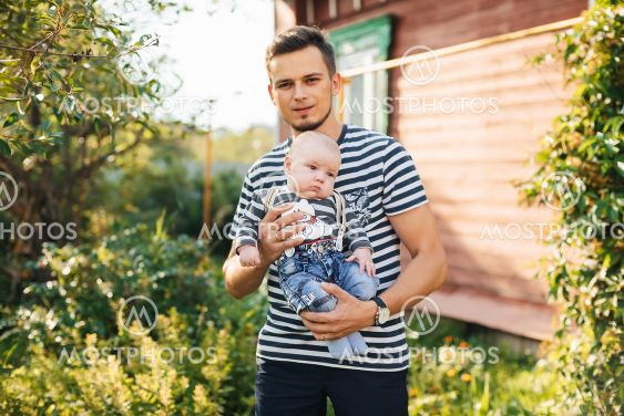 Happy young Caucasian dad with newborn son boy in hands