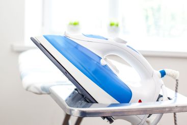 Iron on ironing board on light home interior background