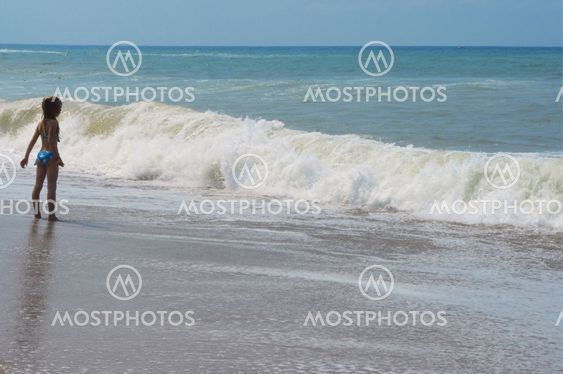 Beach vacation. Small girl and waves.