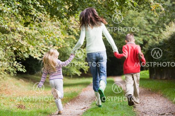 Mother and children running along woodland path