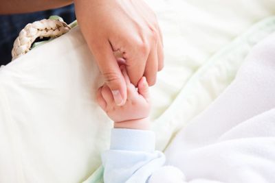 Close-up of a young mother holding her baby's hand