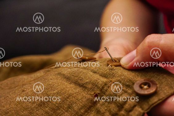 Sewing button of trousers handcraft close up view