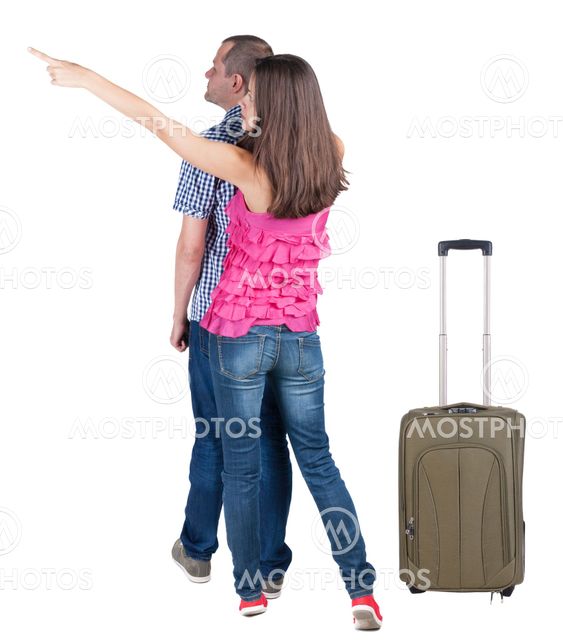 young couple traveling with suitcas and pointing at wal...