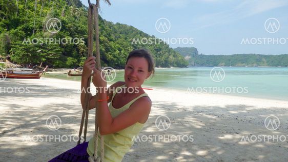 Girl sitting on a swing at beach with seaview