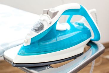 Iron on ironing board on light home interior background