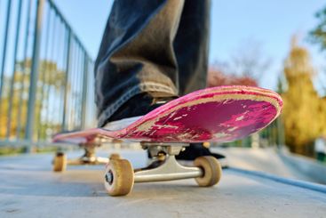 Skateboarder riding on pink skateboard at skatepark