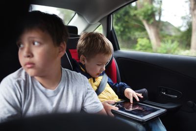 Two boys traveling on the back seat of a car