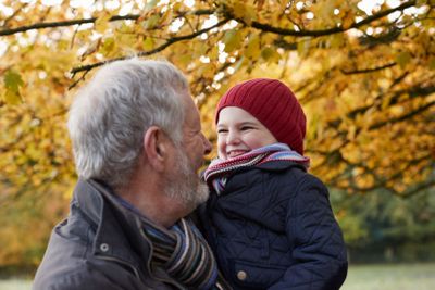 Grandfather Cuddling Granddaughter On Autumn Walk