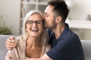 Grateful young son embrace kiss in temple smiling...