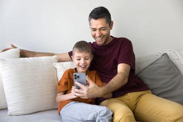 Dad and son spend time on internet using modern smartphone