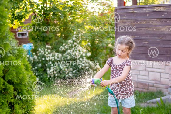 Portrait of little gardener girl, she is watering...